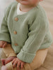 Child wearing a green knitted cardigan with brown buttons on a neutral background Baby Cotton Cardigan - Sage Baby boy