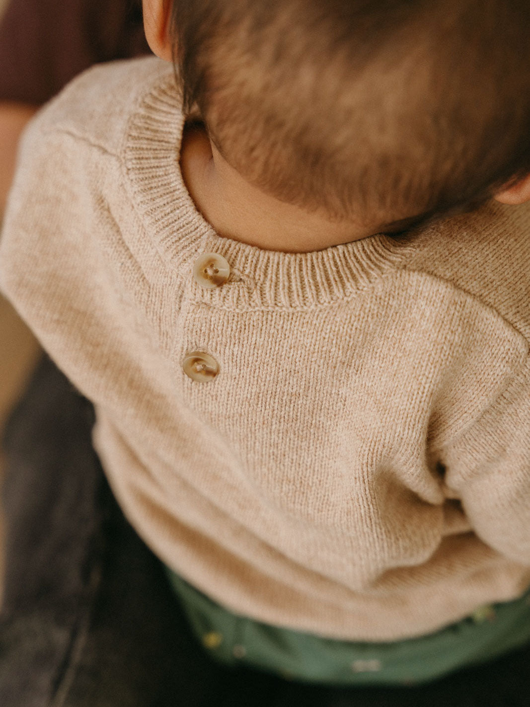 Close-up of a child wearing a beige knitted sweater with two buttons Baby Feature Print Jumper - Little Acorn Baby boy