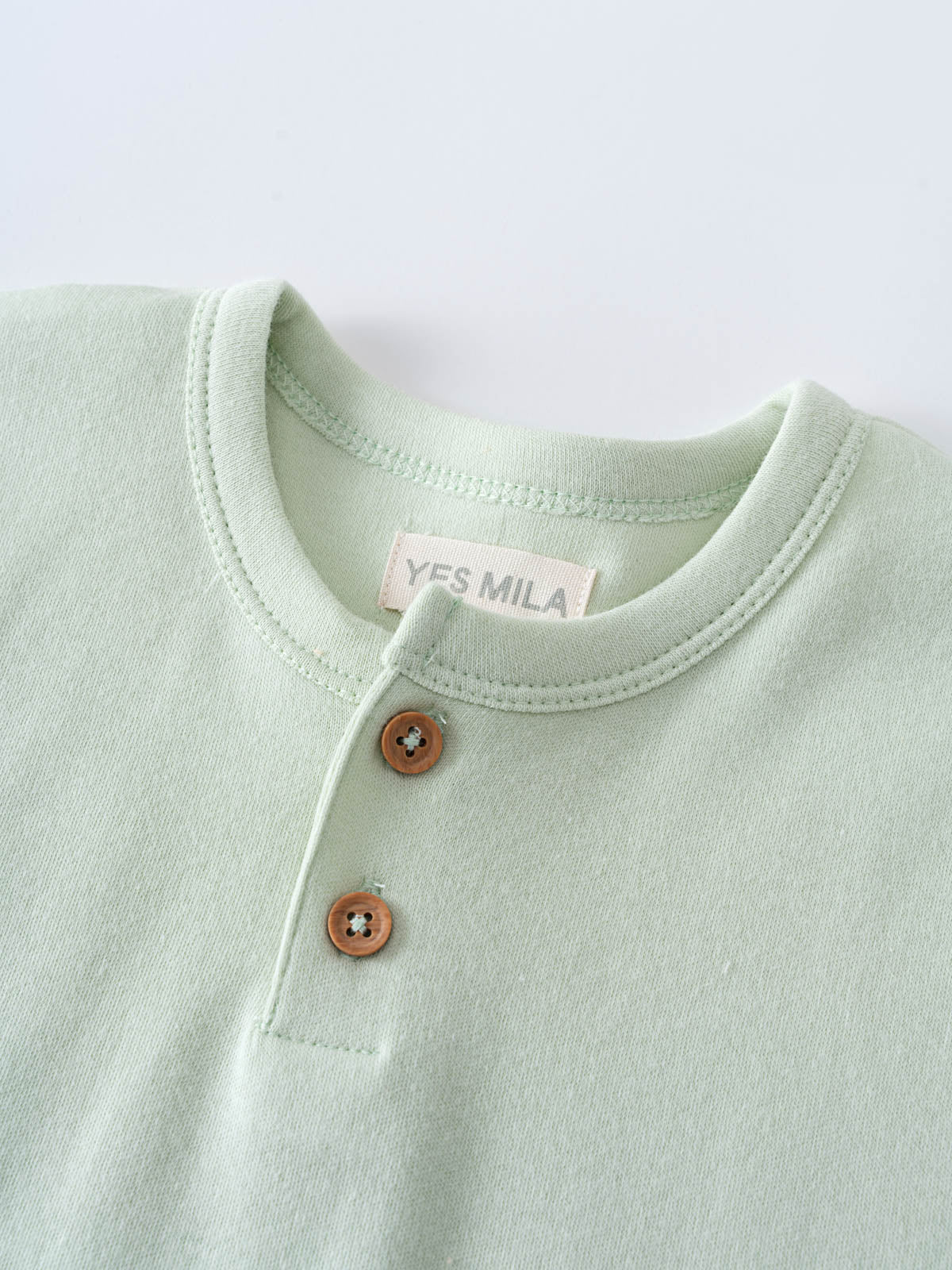 Close-up of a pale green henley shirt with brown buttons Baby Henley Tee - Matcha Baby boy