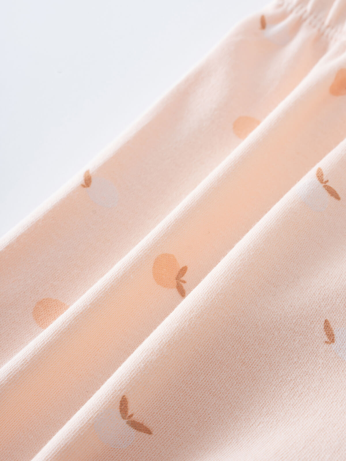 Close-up of peach fabric with small apple print pattern Baby Jersey Shorts - Apples Baby girl
