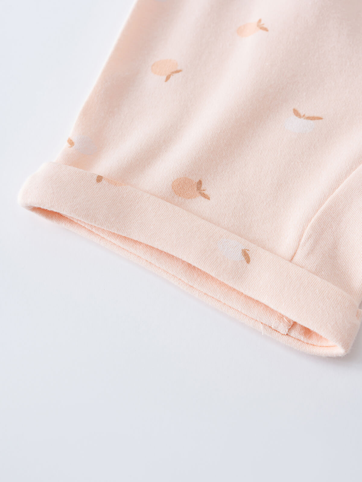 Close-up of pale pink fabric cuff with small peach-colored apple print Baby Jersey Shorts - Apples Baby girl