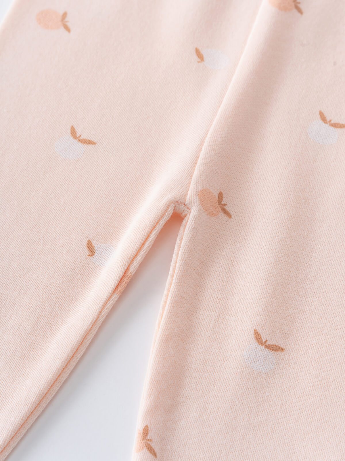 Close-up of pale pink fabric with small orange apple print pattern Baby Printed Leggings - Apples Baby girl