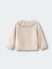 Beige sweater with a ruffled collar on a light gray background