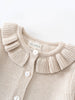 Beige knitted cardigan with ruffled collar and visible brand label on a light background
