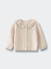 Beige cardigan with ruffled collar on a light gray background