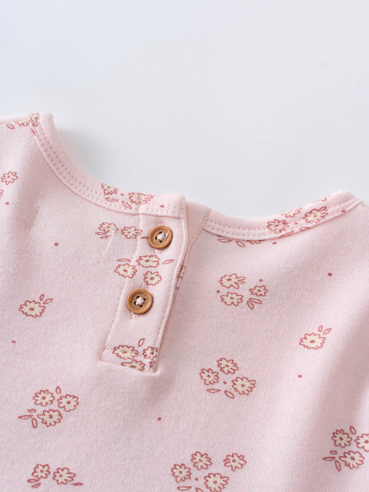 Close-up of pale pink fabric with floral print and wooden buttons Baby Short Sleeve Jersey Dress - Daisy Chain Baby girl
