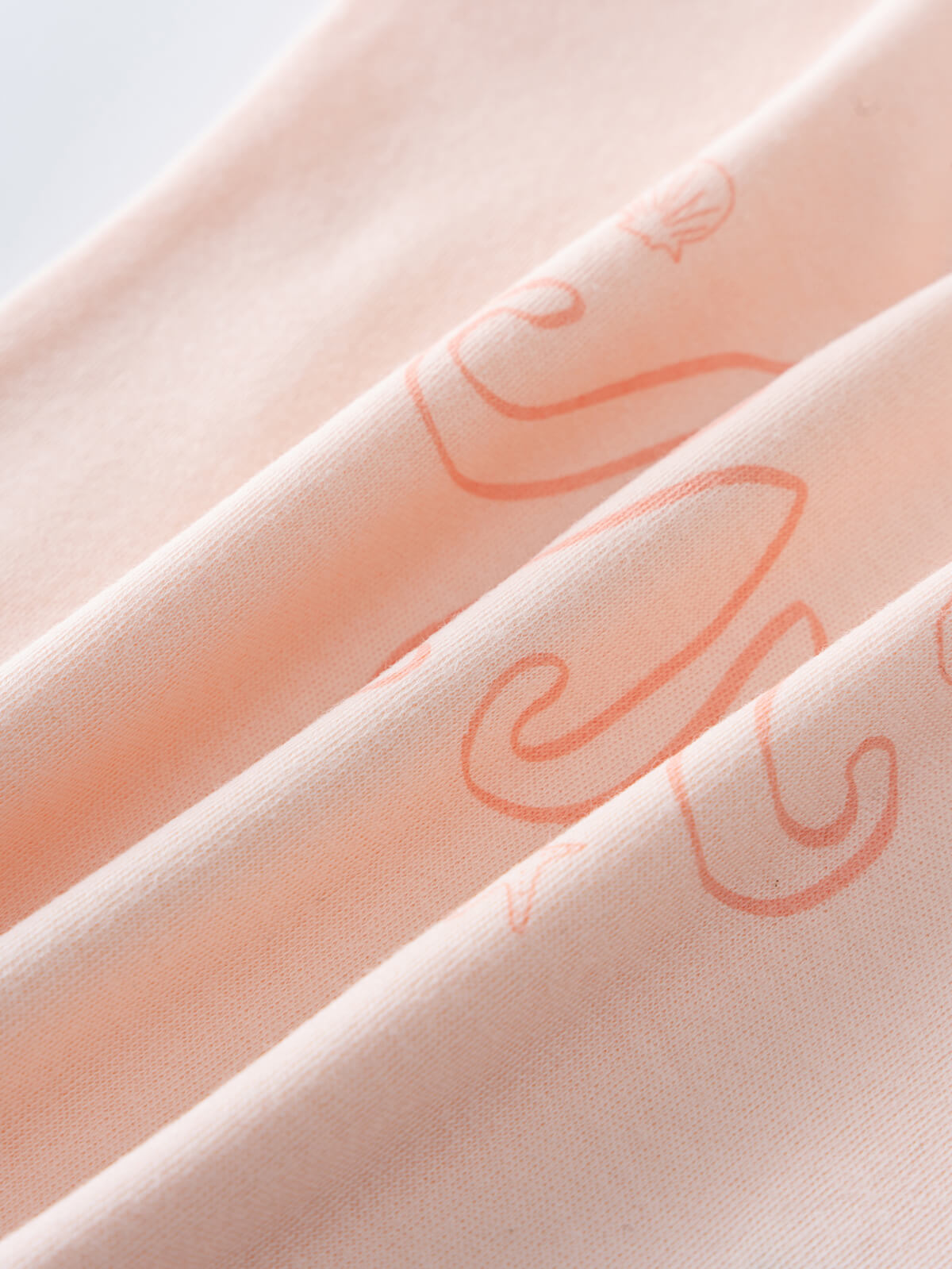 Close-up of peach fabric with orange octopus print design Baby Sleeveless Tee - Octy Baby girl