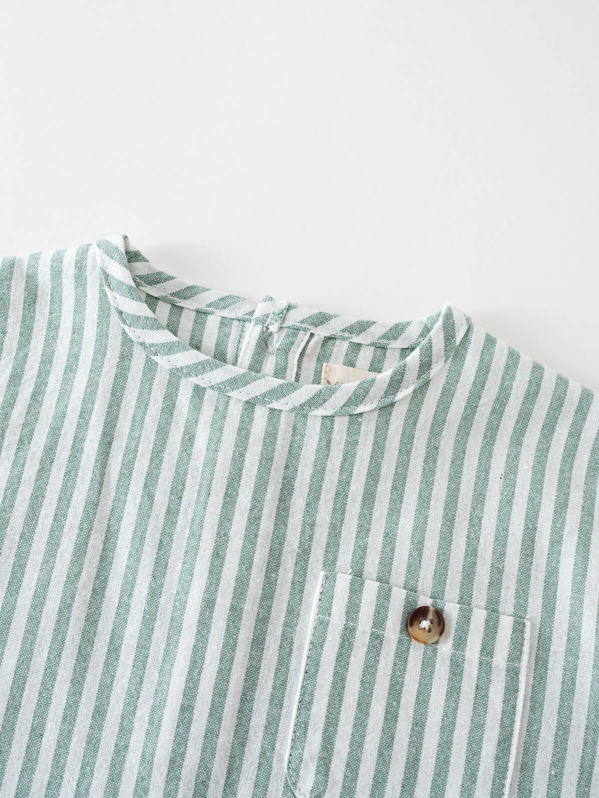 Close-up of green and white striped fabric with brown button detail Woven Stripe Tee Shirt - Mint Stripe Baby boy
