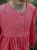 Close-up of a pink dress with buttons on a blurred natural background Button Through Dress - Cloudberry Girls