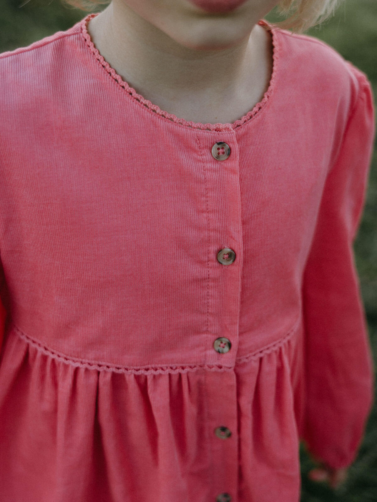 Close-up of a pink dress with buttons on a blurred natural background Button Through Dress - Cloudberry Girls