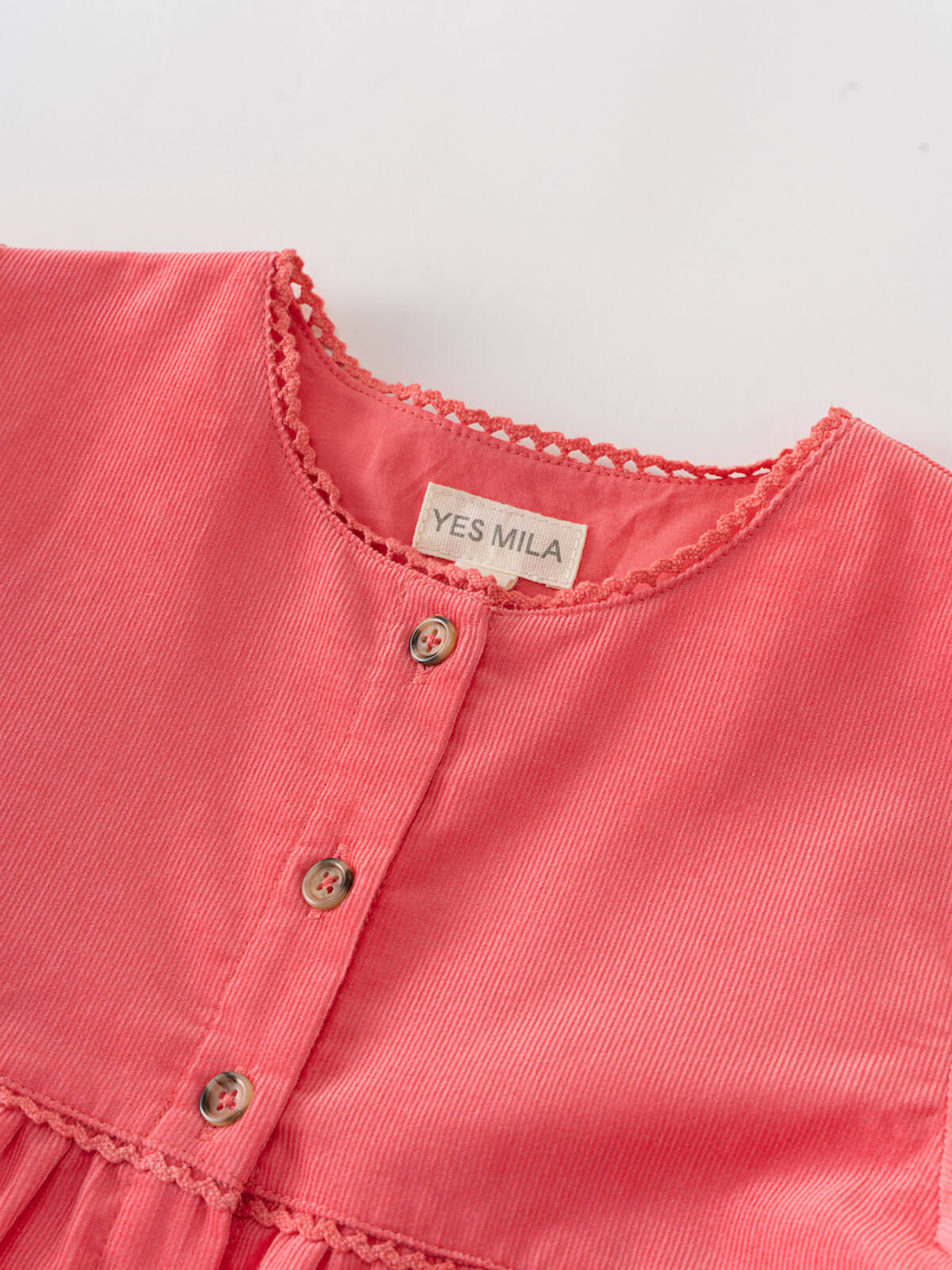 Close-up of a coral pink dress with 'YES MILA' label on a light gray background Button Through Dress - Cloudberry Girls