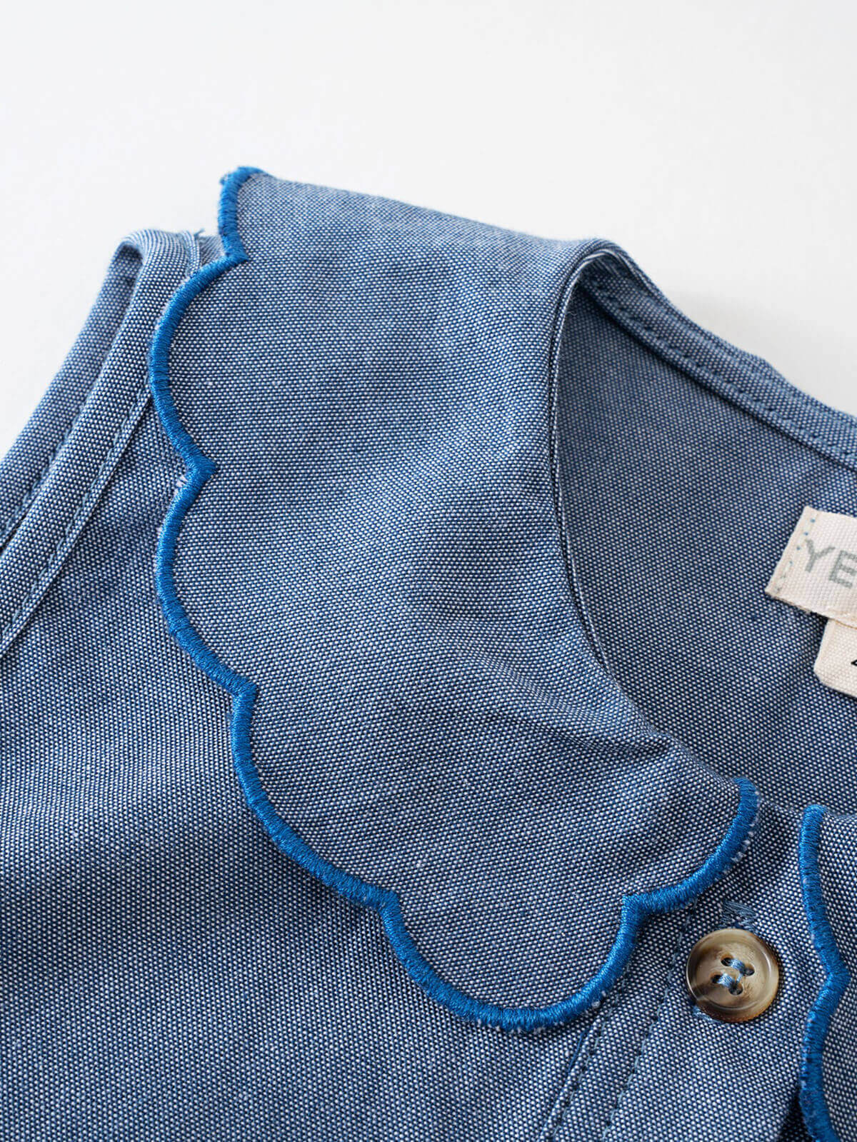 Close-up of blue chambray fabric with contrast stitching and button detail Chambray dress - Blue Chambray Girls