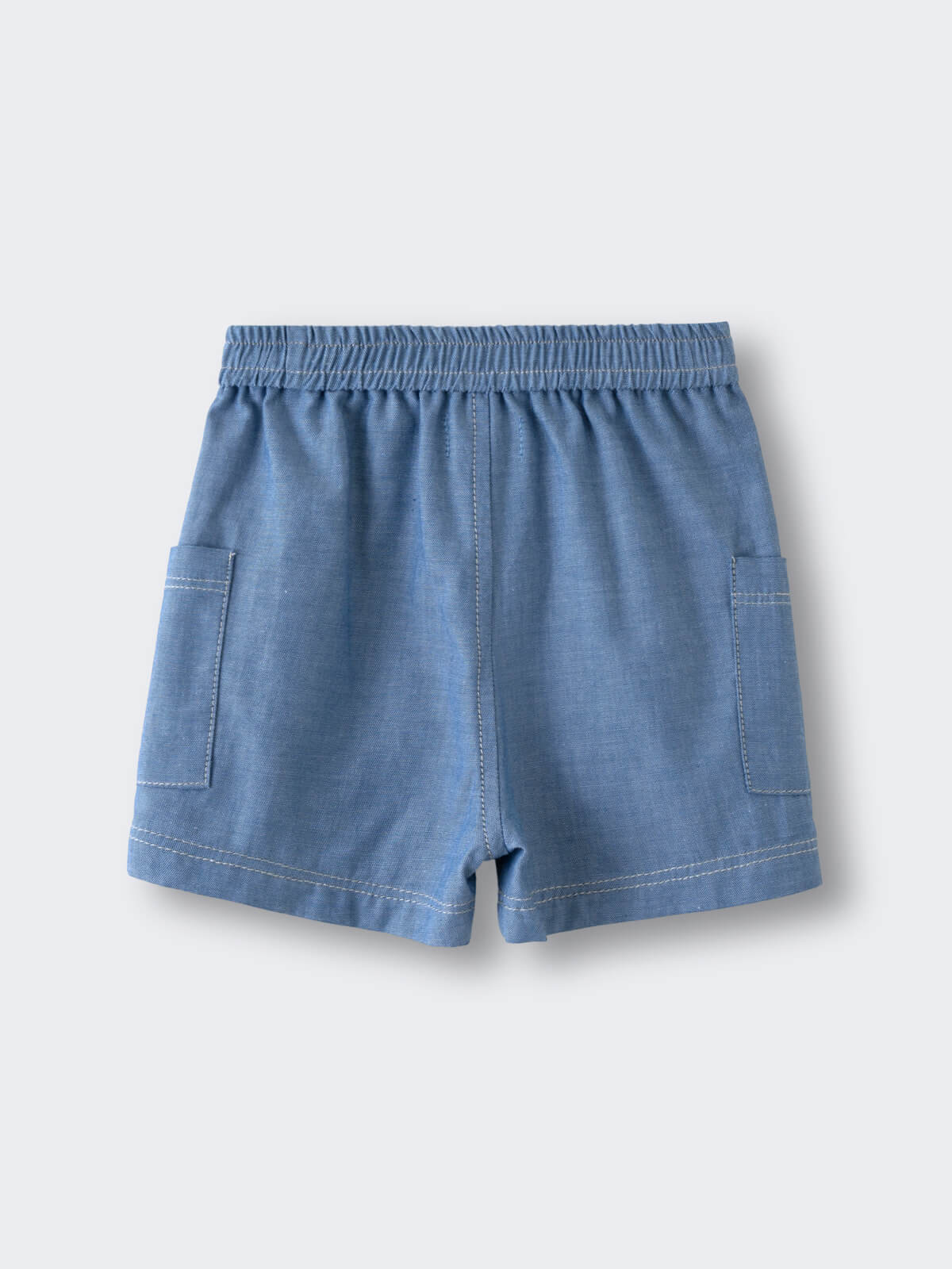 Light blue chambray shorts with elastic waistband and patch pockets laid flat Chambray Shorts - Blue Chambray Baby boy