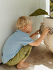 Child playing with a decorative stone sculpture against a white wall.