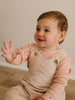 Baby wearing a pink long-sleeve shirt and beige overalls, sitting on a wooden floor. Corduroy Overalls - Clay Baby boy