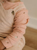 Close-up of a child's outfit with a pink long-sleeve shirt and beige ribbed sweater. Corduroy Overalls - Clay Baby boy