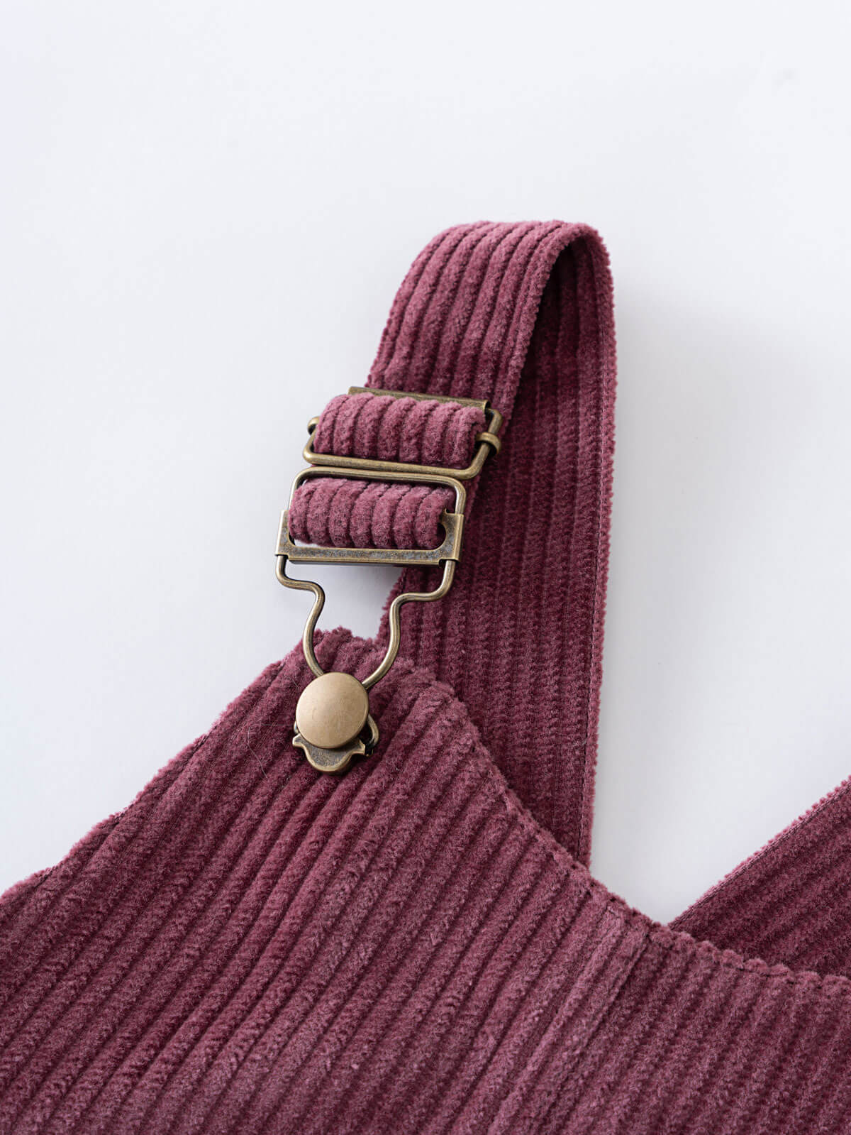 Close-up of a plum corduroy pinafore dress with a strap and button detail on a white background Corduroy Pinafore Dress - Plum Jam Girls