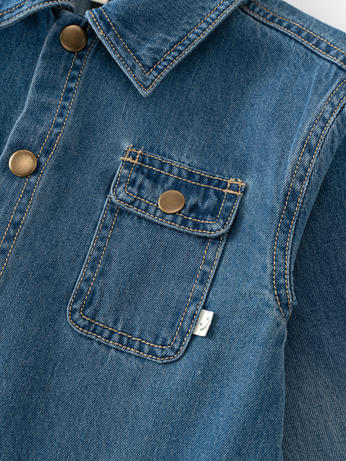 Close-up of a blue denim jacket with a pocket and buttons. Denim Jacket - Blue Denim Girls and Boys
