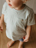 Child wearing a striped shirt with a pocket on a neutral background