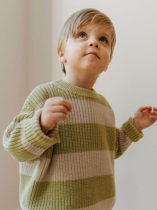 Child wearing a green and beige striped sweater against a plain background