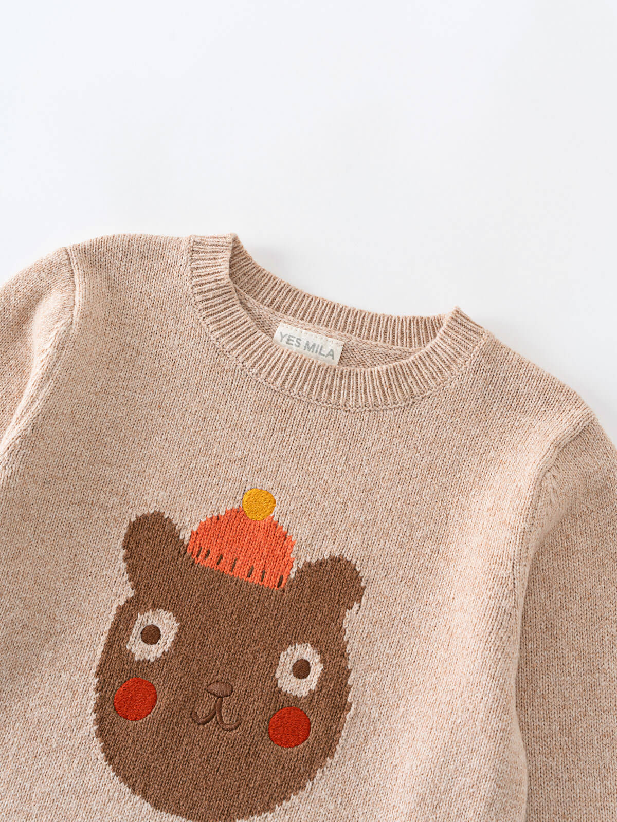 Children's sweater with bear face design and 'Yes Mila' label on a white background