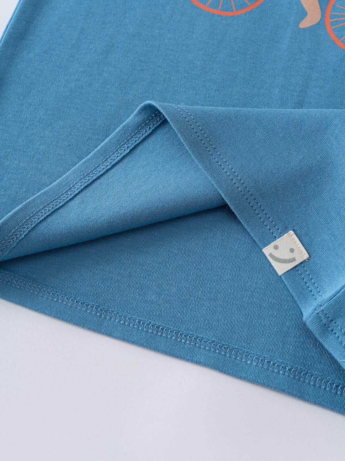 Close-up of blue t-shirt hem with small smiley face label detail feature print Short Sleeve Tee - Milo Biking Boys