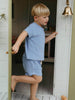 Child in a blue outfit standing in a doorway