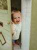 Child peeking out from a playhouse door with a smile
