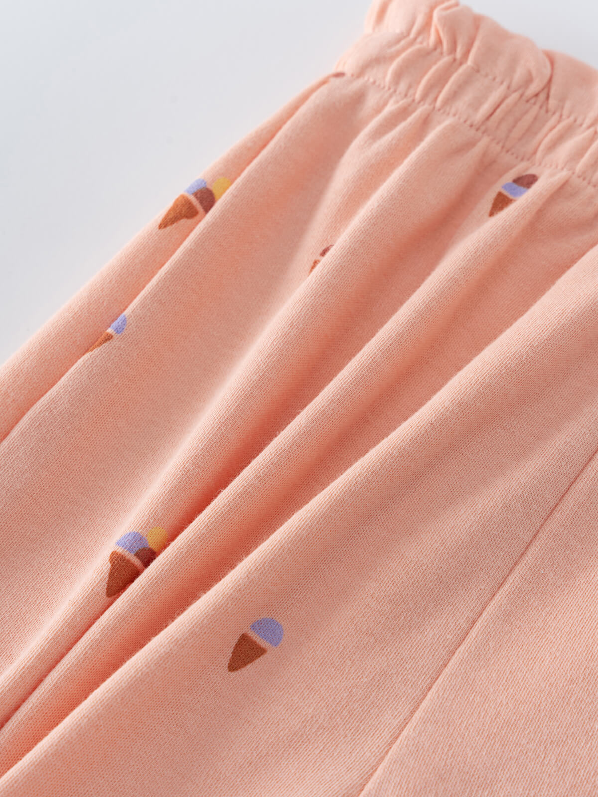 Close-up of peach fabric with scattered ice cream cone pattern detail Jersey Shorts - Ice Creams Girls