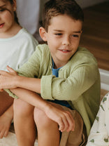 Young boy in a green shirt sitting on the floor with a blurred background