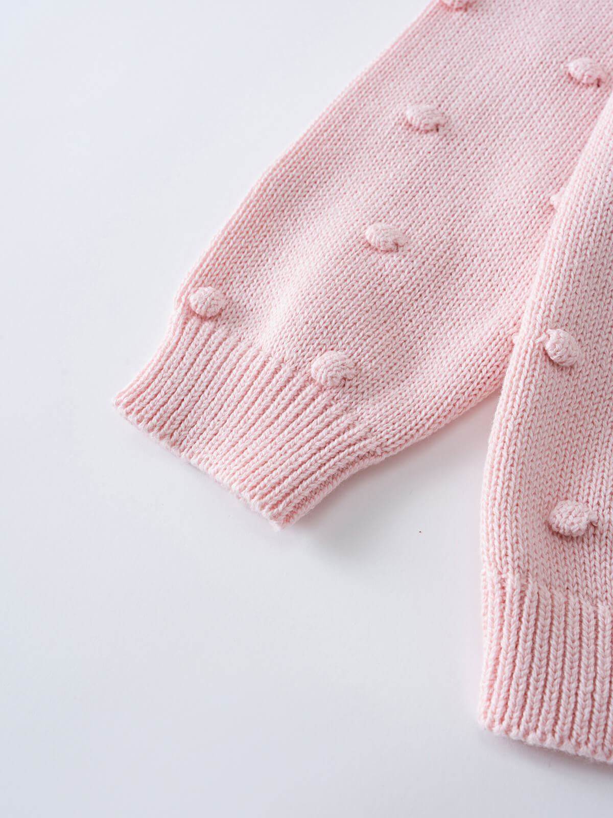 Close-up of pink knitted sweater sleeve with textured bobble details Knit Jumper - Candy Floss Girls