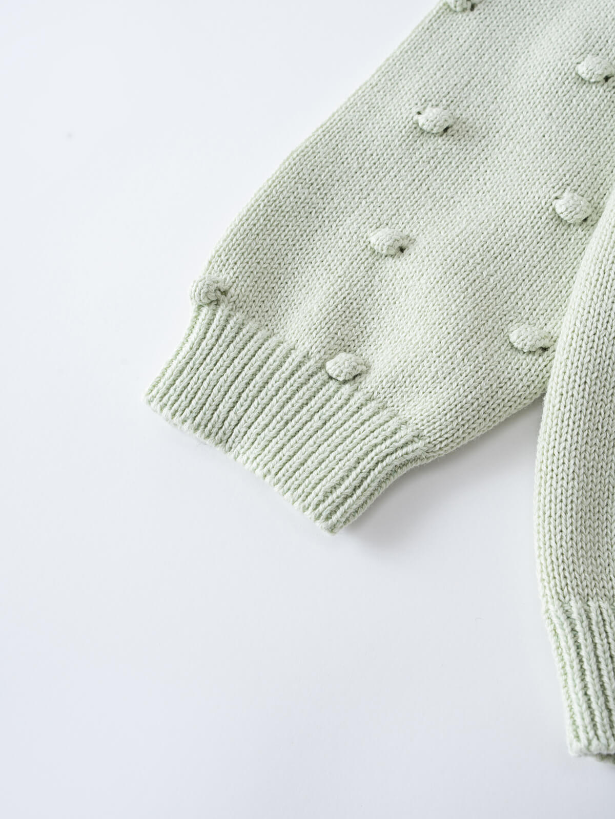 Close-up of a pale green knitted sweater sleeve with textured dots Knit Jumper - Mint Girls