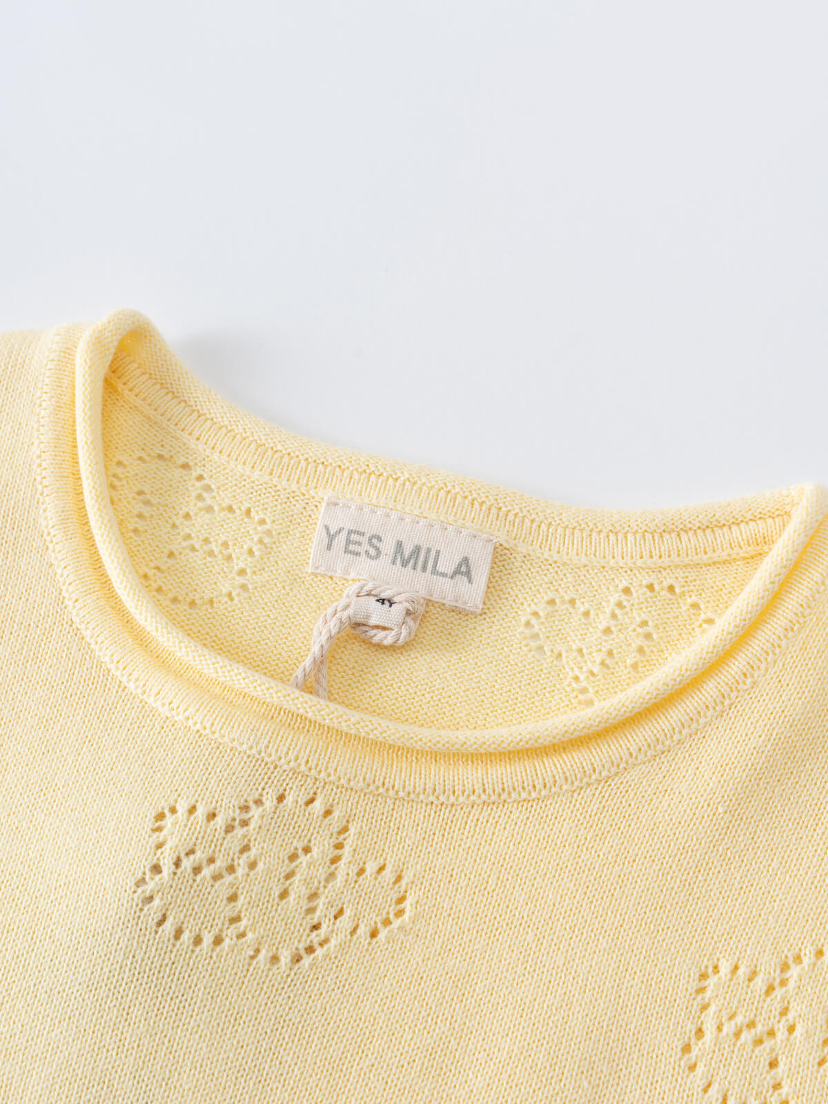 Close-up of a pale yellow knit garment showing neckline and label detail Knit Tee - Sun Soaked Girls