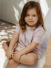 Young child sitting on a white surface with a neutral background