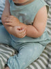 Baby in light blue outfit sitting on a striped surface