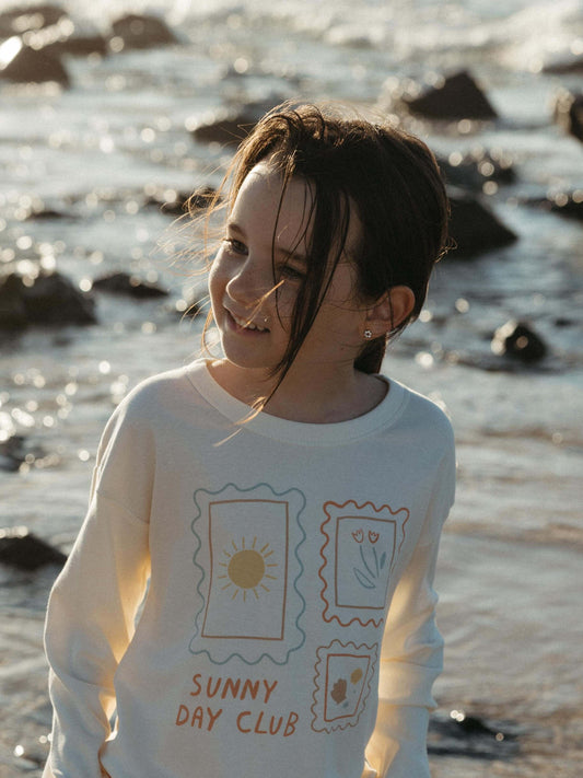 Girl walking on the sand wearing a white long sleeve tee