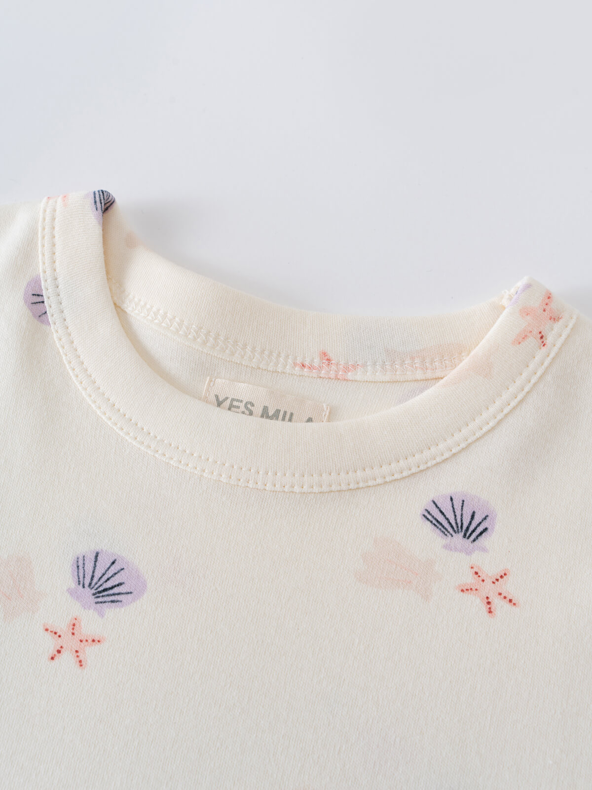 Close-up of cream-colored garment with purple shell and coral starfish pattern Lottie Short Sleeve Dress - Beach Shells Girls