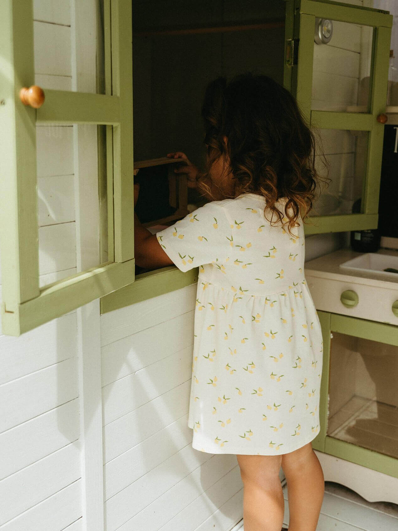 Child playing with wooden toys in a green play kitchen.