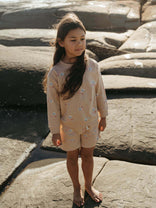 Young girl in a beige outfit standing on rocky terrain