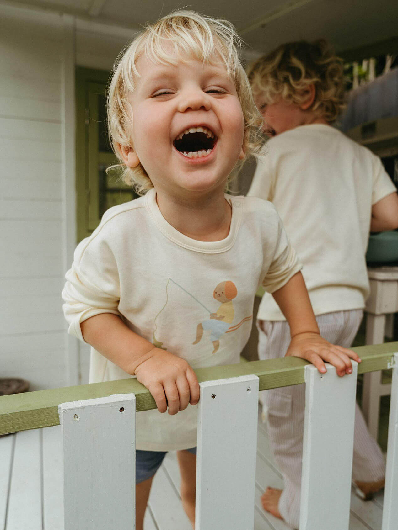 Child laughing while standing on a wooden deck