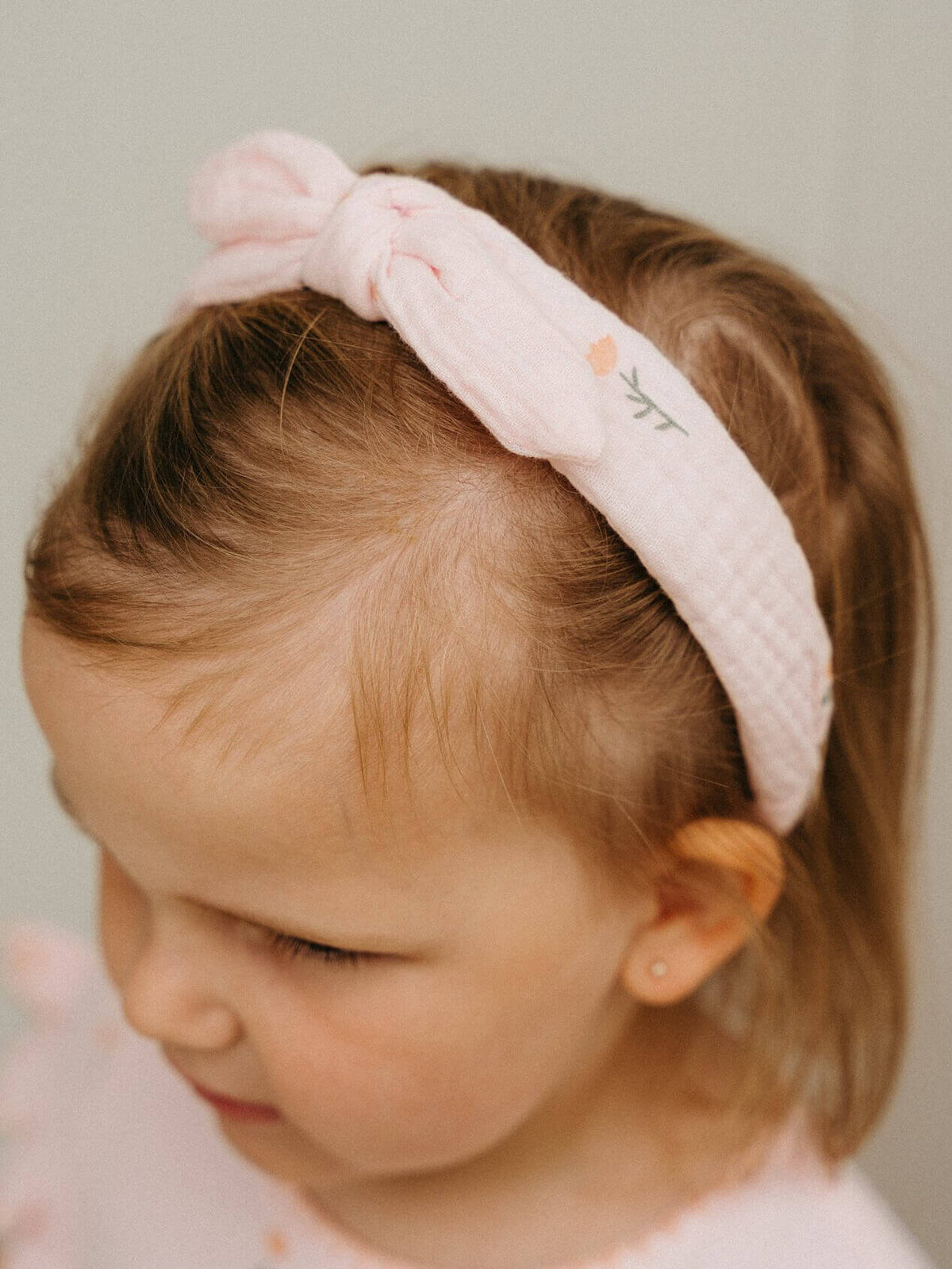 Child wearing a pink headband with a subtle design on a plain background Muslin Headband - Poppy Field Girls