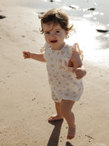 baby toddler girl walking on the beach wearing a floral printed romper