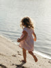 Girl running on the beach wearing a pink dress