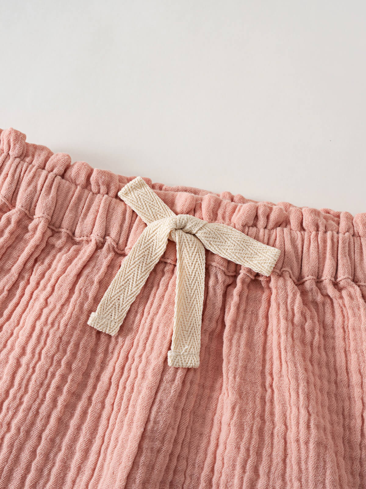 Close-up of pink crinkled cotton shorts with cream drawstring tie Muslin Shorts - Toasted Peach Girls
