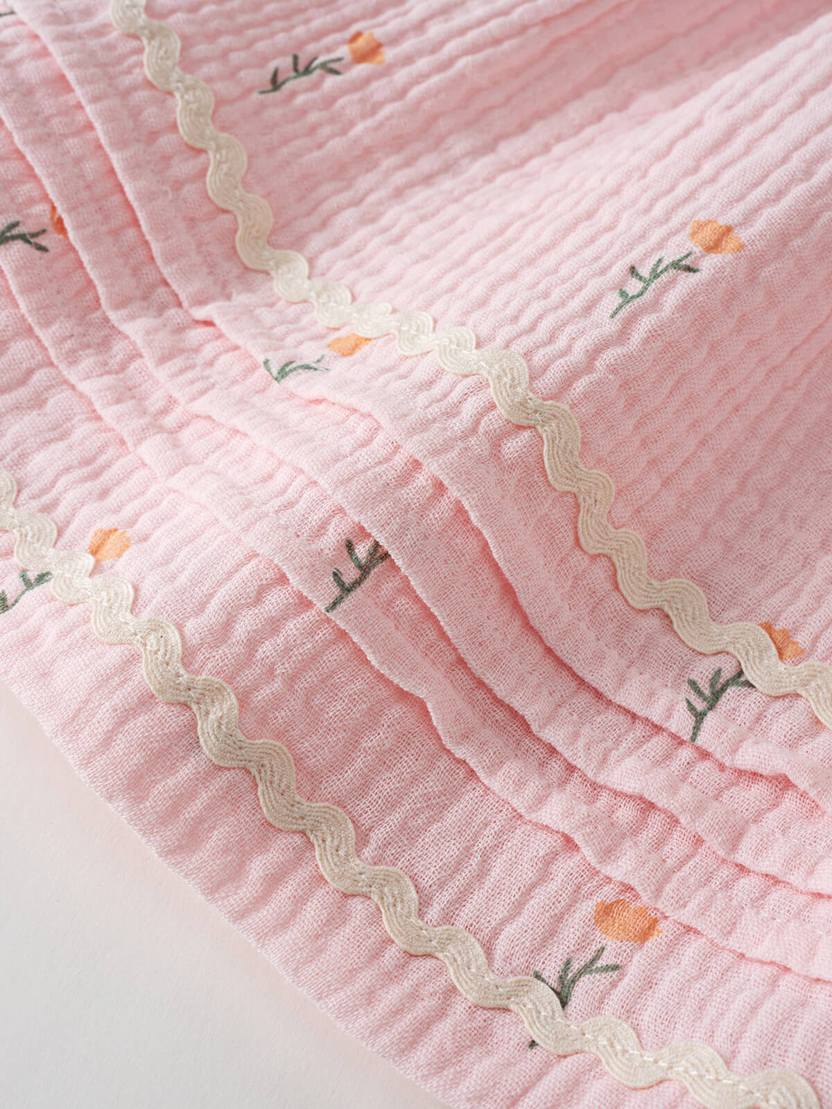 Close-up of pink textured fabric with white wavy trim and small floral embroidery Muslin Skirt - Poppy Field Girls
