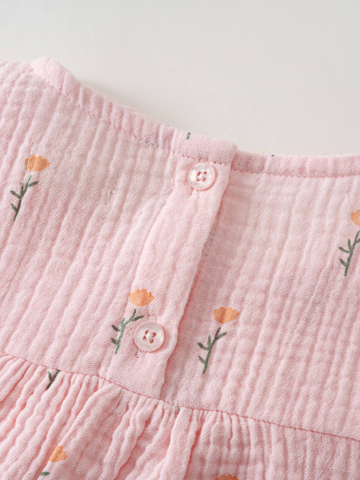 Close-up of pink textured fabric with floral embroidery and white buttons Muslin Top - Poppy Field Girls