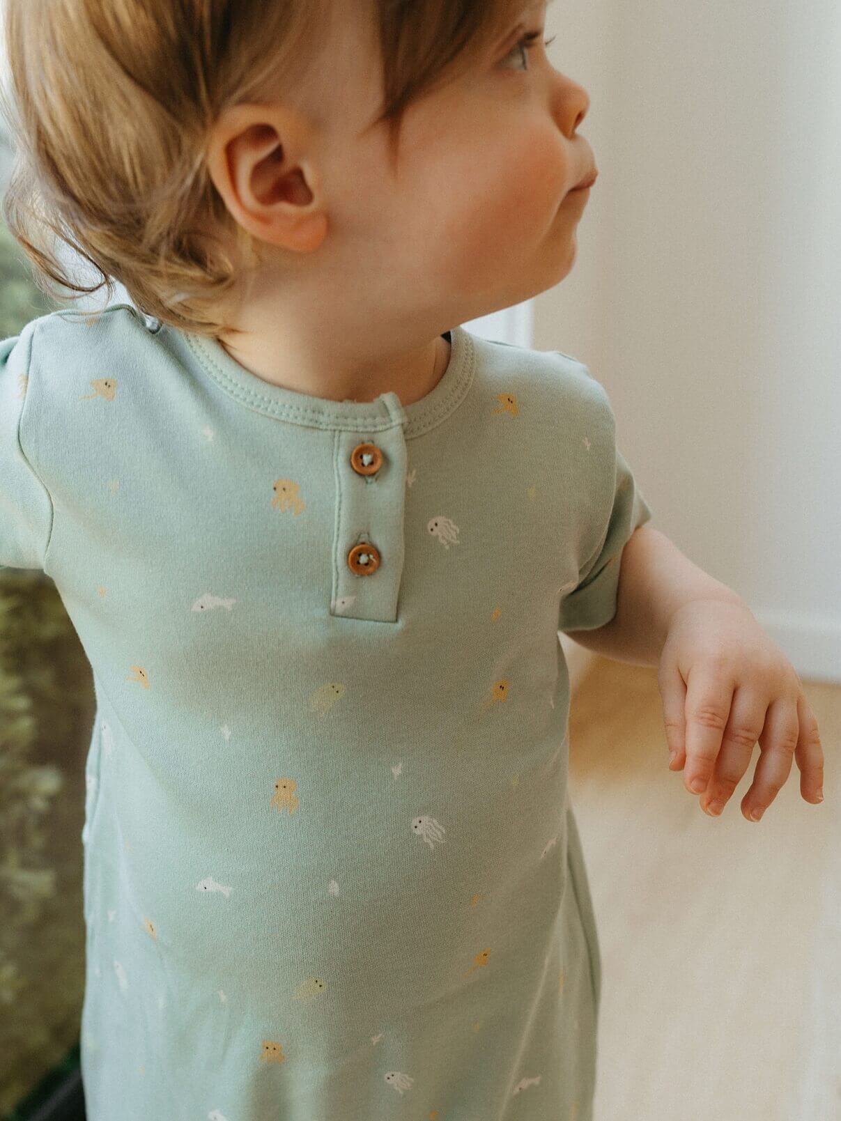 Child wearing a light blue dress with fish patterns indoors