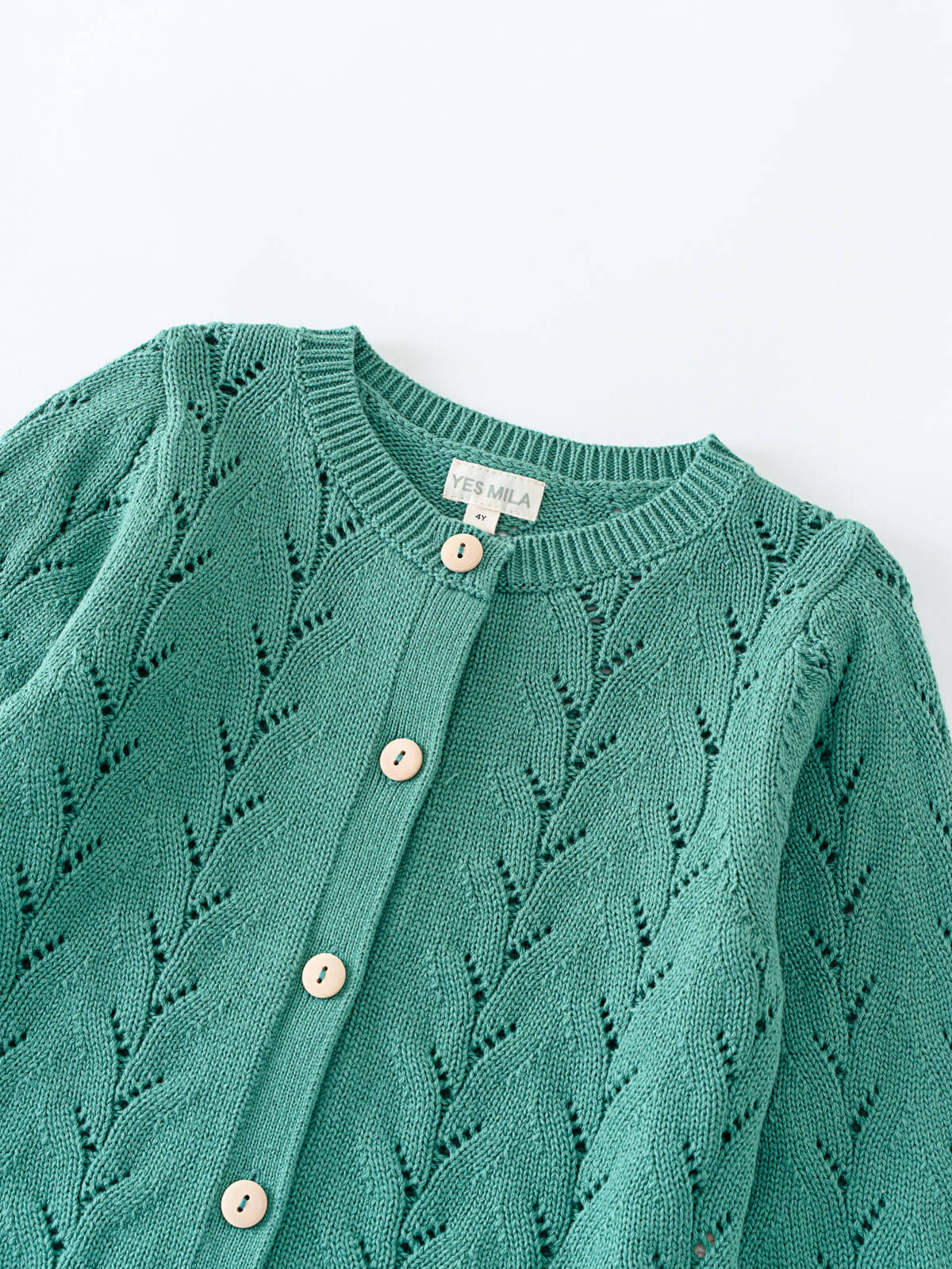 Green knitted cardigan with button details on a light gray background Pointelle Cardigan - Balsam Girls