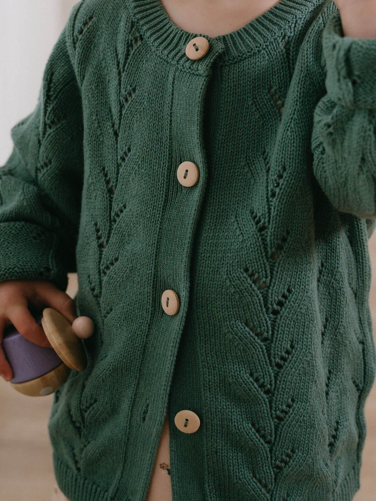 Green knitted cardigan with wooden buttons on a neutral background Pointelle Cardigan - Balsam Girls