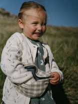 Child holding a checkered bag outdoors with grass and blue sky in the background Pointelle Cardigan - Ecru Girls